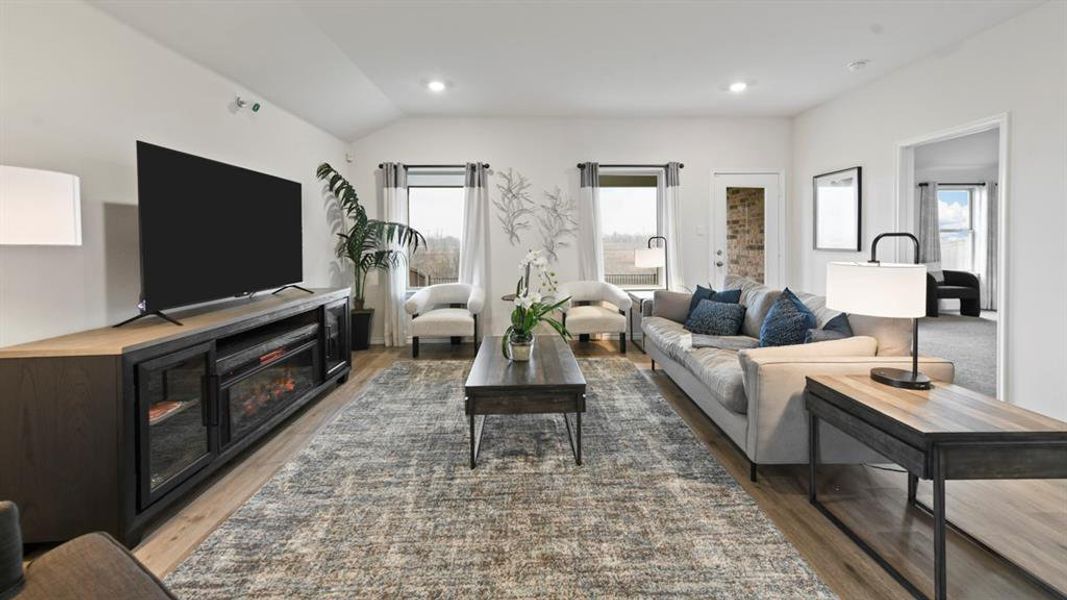 Spacious living area featuring light wood-finish flooring and a vaulted ceiling Spacious living area featuring light wood-finish flooring and a vaulted ceiling