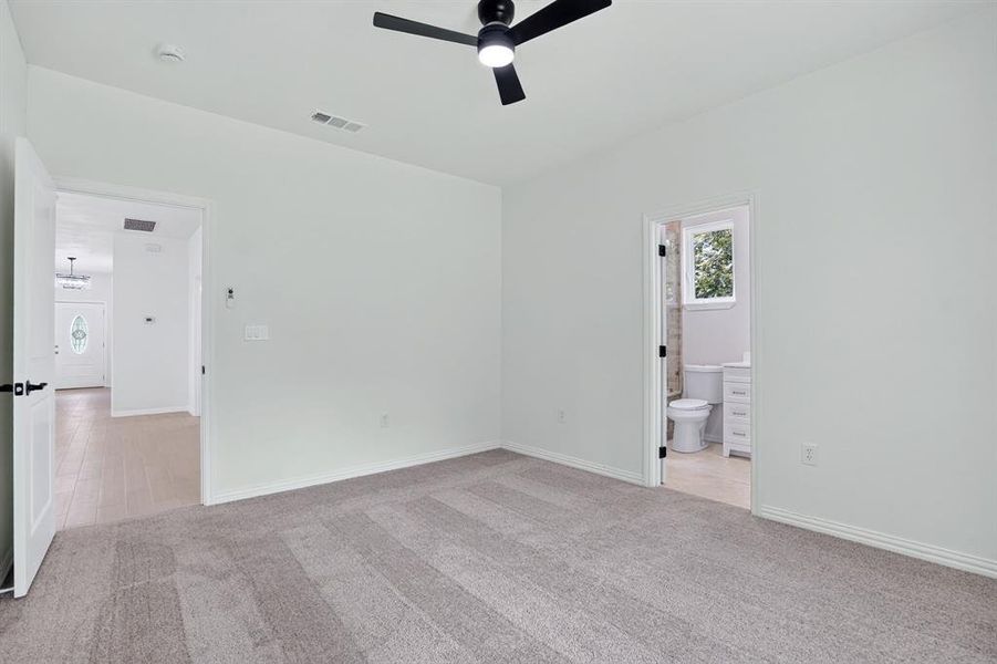 Carpeted interior space featuring a matte black ceiling fan, white trim, and light-toned walls