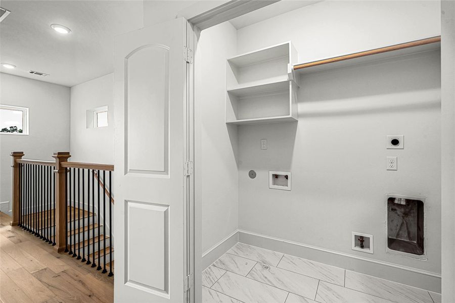 Utility room with hookups for a washer and dryer, tiled flooring, and built-in shelving for convenient storage and organization.