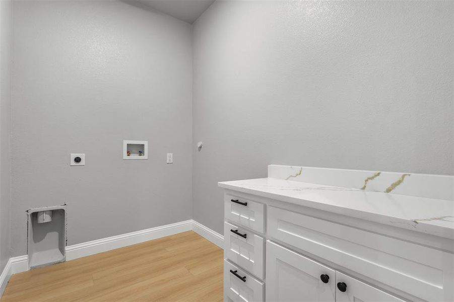 Laundry room with light wood-type flooring, electric dryer hookup, washer hookup, and cabinet space
