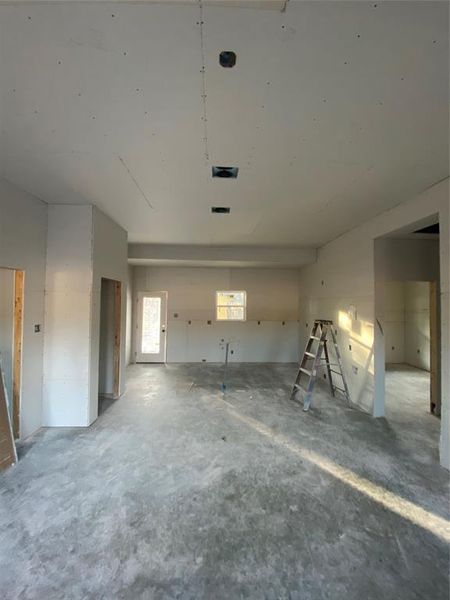 Unfurnished living room with unfinished concrete flooring and a garage