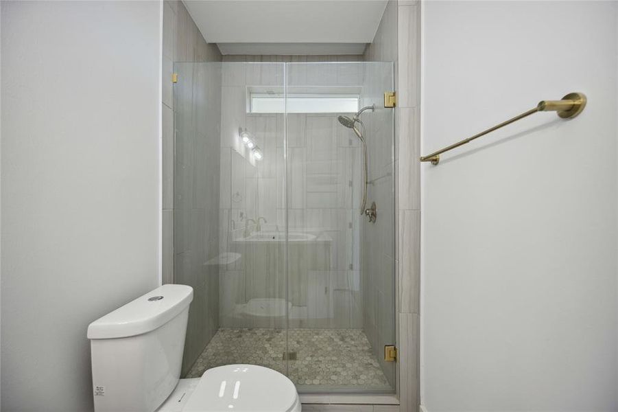 Discover the convenience of a sleek main-level bathroom featuring a glass-enclosed walk-in shower and contemporary finishes.