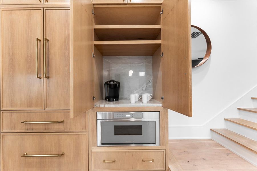 Custom white oak cabinetry with hidden coffee area and built-in microwave.