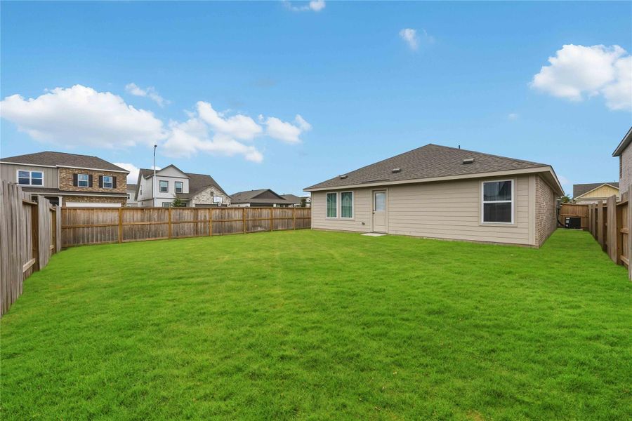 Expansive fenced backyard with lush green lawn, ideal for outdoor activities and gatherings.