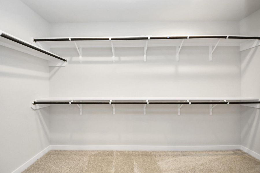 Walk-in closet that epitomizes luxury and practicality. This generously sized space features built-in shelving, offering abundant room for impeccable organization. High ceilings and recessed lighting create a bright and welcoming ambiance. Sample photo of completed home with similar floor plan. Actual colors and selections may vary.
