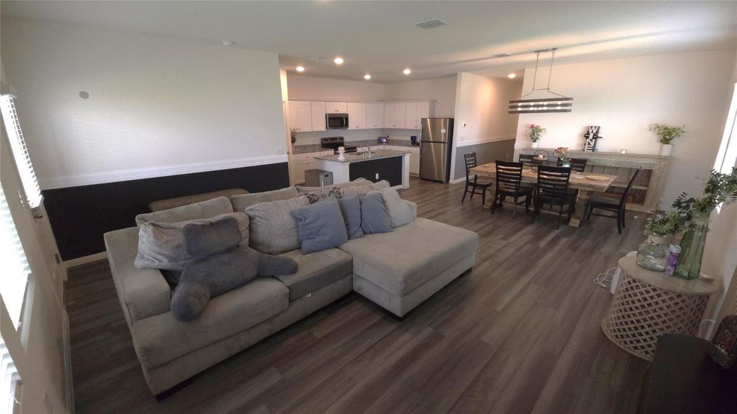 Open-concept living space featuring wood-finish flooring, recessed lighting, and a two-toned wall