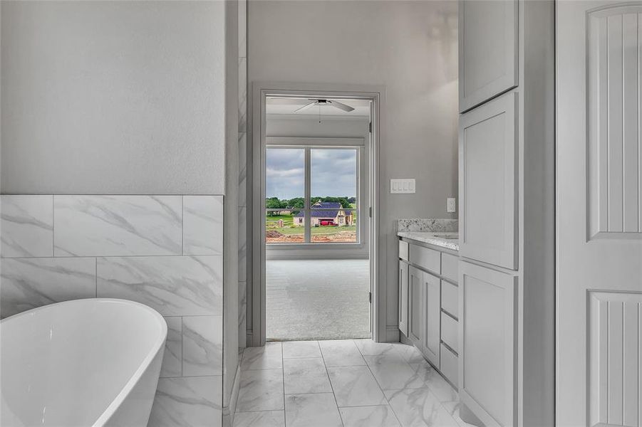 Bathroom featuring tile walls, a bath, and vanity