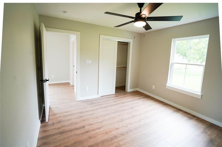 Unfurnished bedroom featuring light wood-style flooring, a closet, and ceiling fan