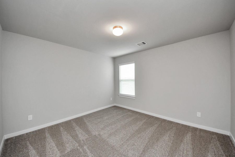 Secondary bedroom features plush carpeting, large windows that let in plenty of natural light, bright paint, and spacious closets.