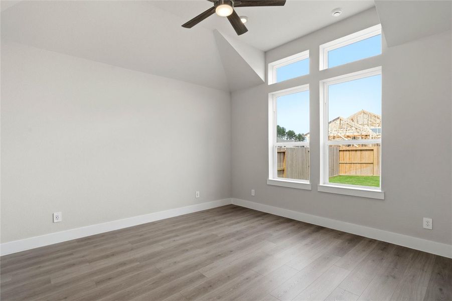 Retreat to this bright and airy primary bedroom, a serene sanctuary designed for ultimate relaxation and comfort. Vaulted ceilings, large windows, stylish laminate flooring, and modern ceiling fan give this room a peaceful space to come home to.