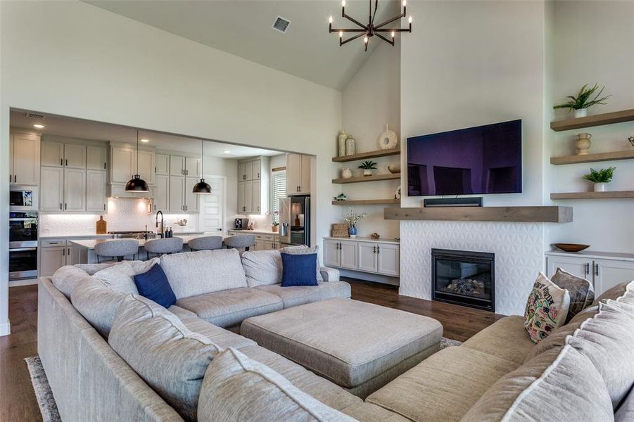 Living area featuring high vaulted ceiling, a chandelier, dark wood-style floors, and a glass covered fireplace Living area featuring high vaulted ceiling, a chandelier, dark wood-style floors, and a glass covered fireplace