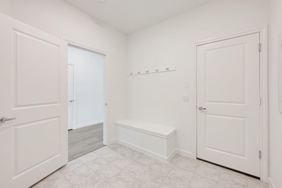 Mudroom with built-in bench, wall hooks, white walls, and tile flooring Mudroom with built-in bench, wall hooks, white walls, and tile flooring
