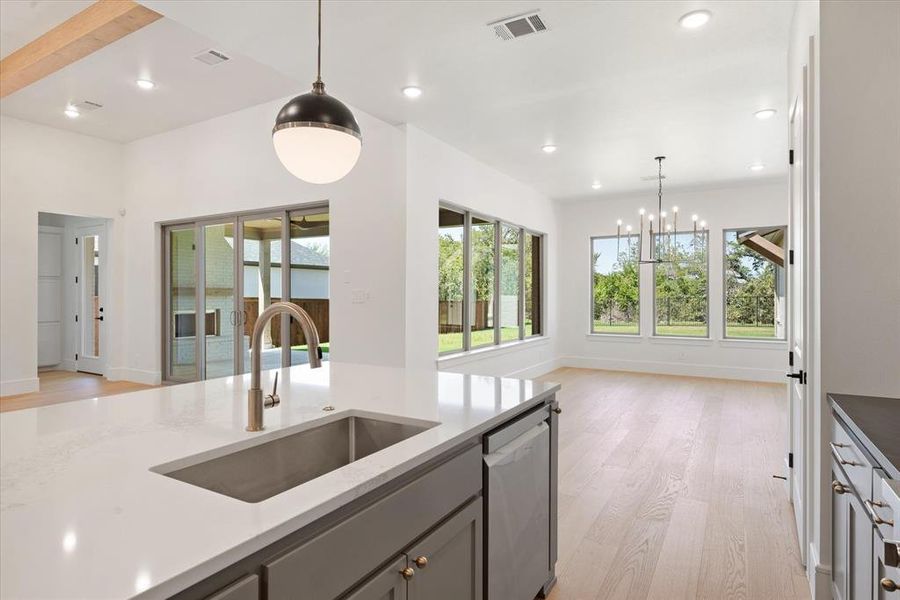 Kitchen featuring a wealth of natural light, stainless steel dishwasher, sink, and decorative light fixtures