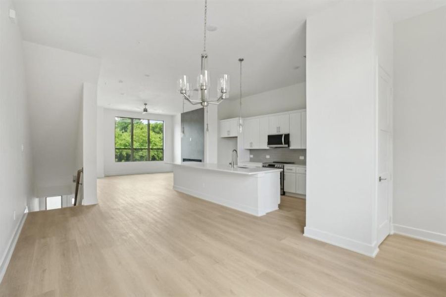 Kitchen featuring open floor plan, a chandelier, light wood-style floors, a sink, and white cabinets