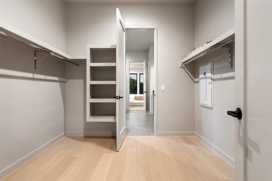 Functional custom shelving and light hardwood flooring define this ample walk-in closet. Functional custom shelving and light hardwood flooring define this ample walk-in closet.