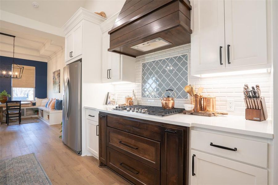 Two tone kitchen with light wood-style flooring, stainless steel appliances, dual tone cabinetry, tasteful backsplash, and light stone countertops Two tone kitchen with light wood-style flooring, stainless steel appliances, dual tone cabinetry, tasteful backsplash, and light stone countertops