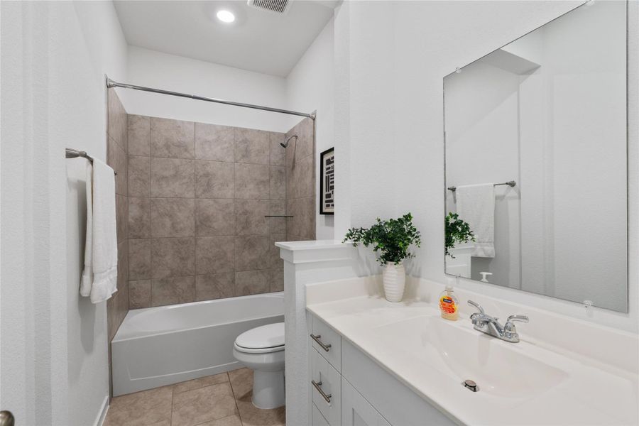 A pristine bathroom featuring a tiled shower, bathtub combination, and a contemporary vanity with a large mirror.