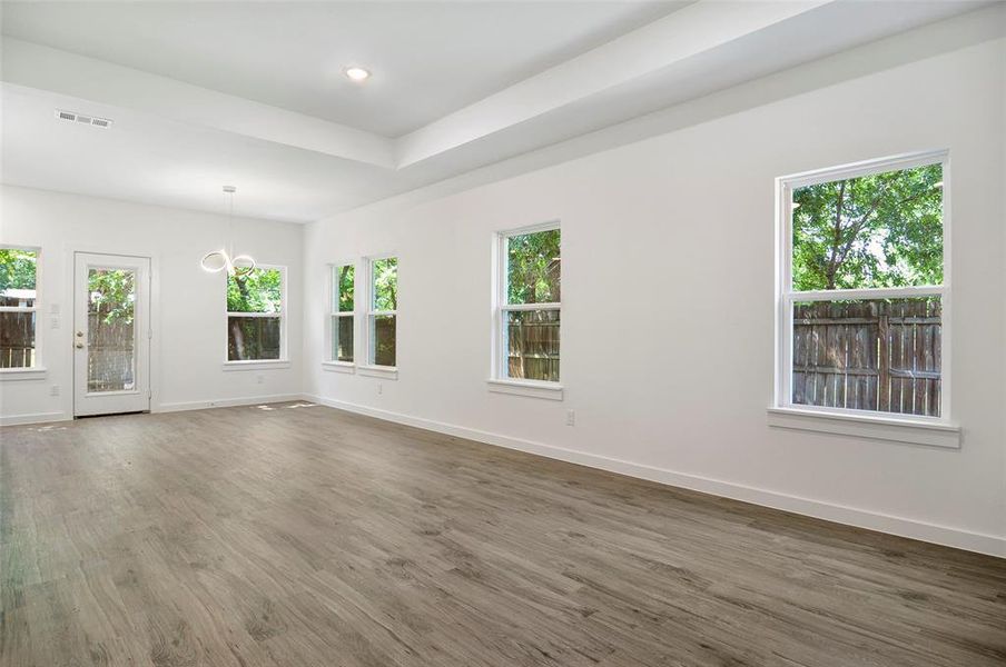 Unfurnished living room with an inviting chandelier, wood-type flooring, and plenty of natural light