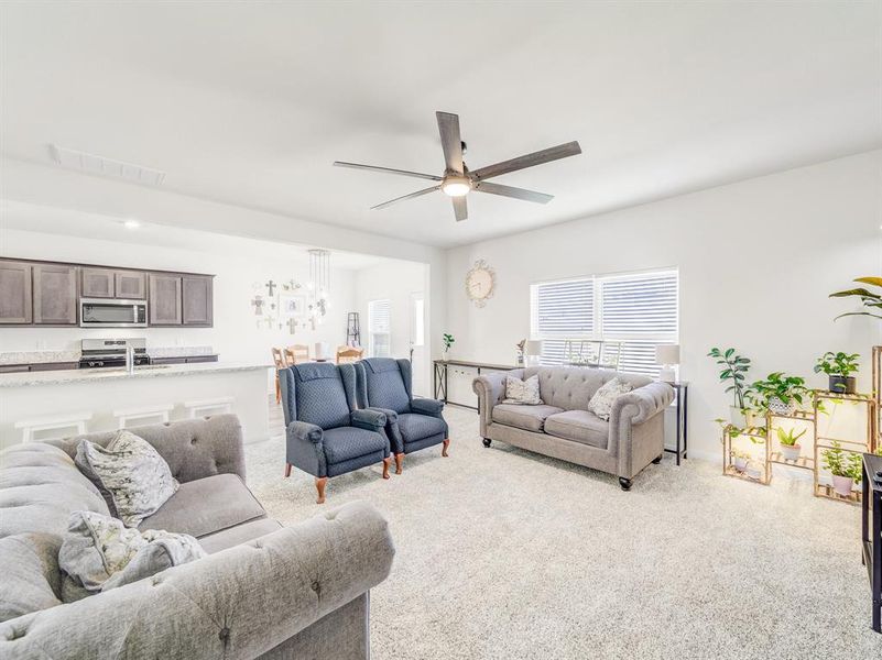 Carpeted living room with ceiling fan and baseboards