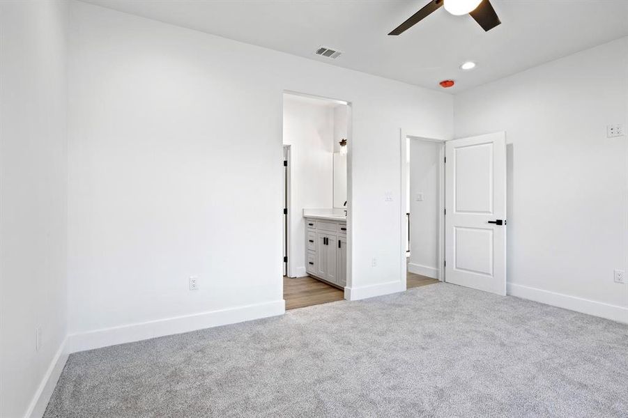 Unfurnished bedroom featuring baseboards, recessed lighting, connected bathroom, visible vents, and carpet Unfurnished bedroom featuring baseboards, recessed lighting, connected bathroom, visible vents, and carpet