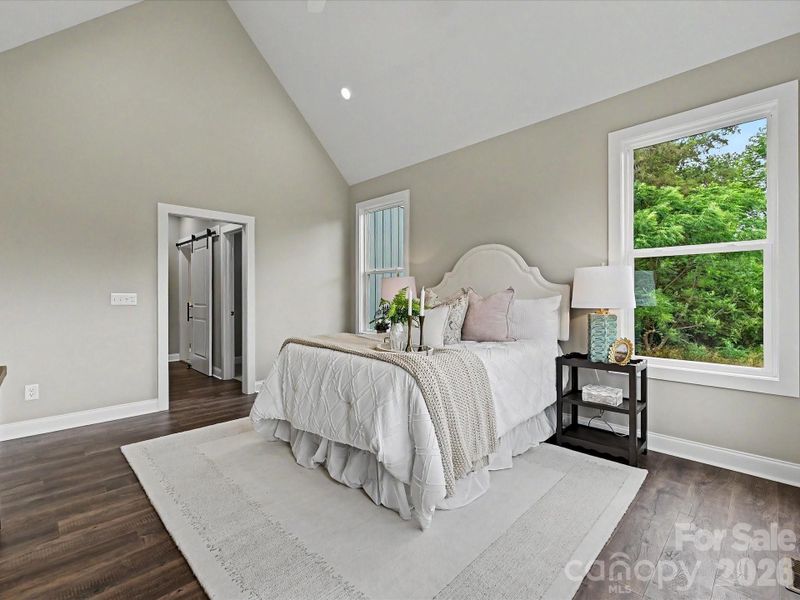 Spacious primary suite features soaring vaulted ceilings, abundant natural light, and peaceful views of the private backyard.