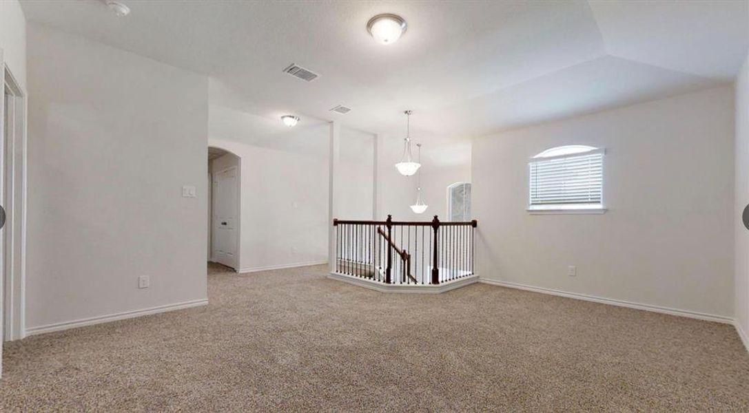Carpeted empty room featuring arched walkways and baseboards