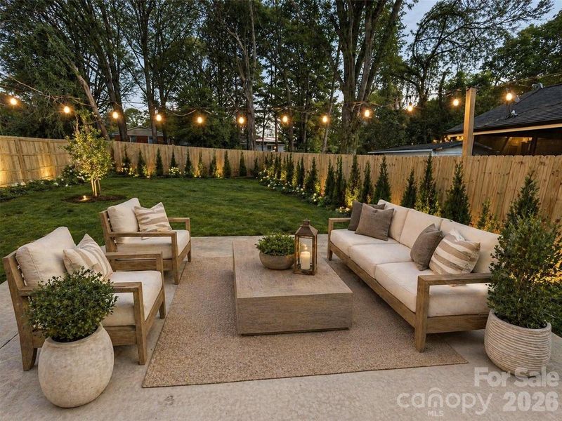 Fenced yard. Bushes and patio furniture are virtually staged
