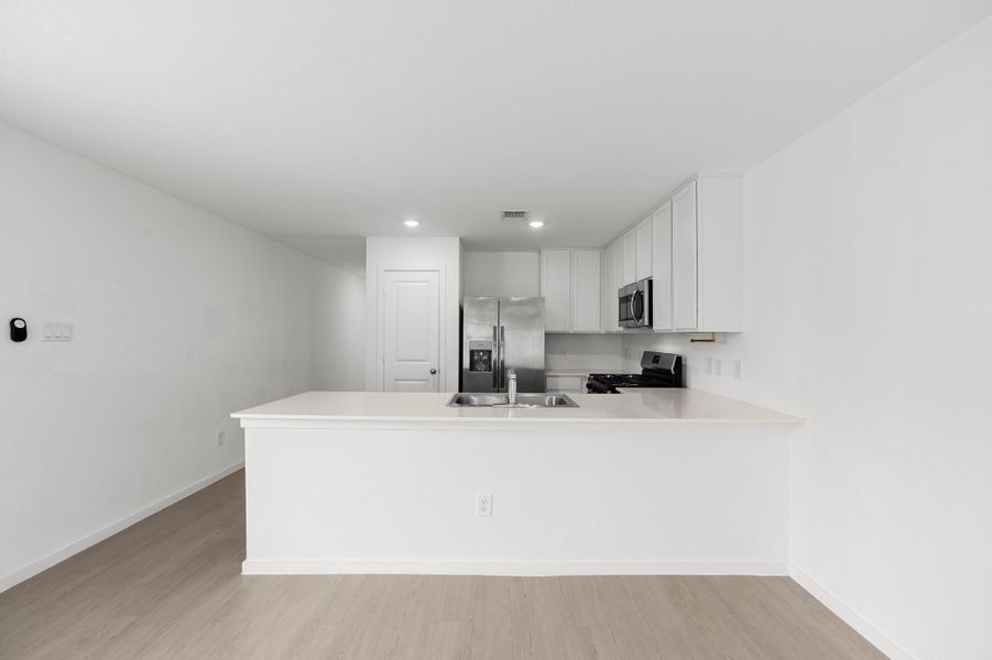 Expansive peninsula provides ample prep and serving space while keeping the kitchen visually connected to the surrounding living areas. Crisp white cabinetry pairs with stainless steel appliances for a streamlined finish. Expansive peninsula provides ample prep and serving space while keeping the kitchen visually connected to the surrounding living areas. Crisp white cabinetry pairs with stainless steel appliances for a streamlined finish.