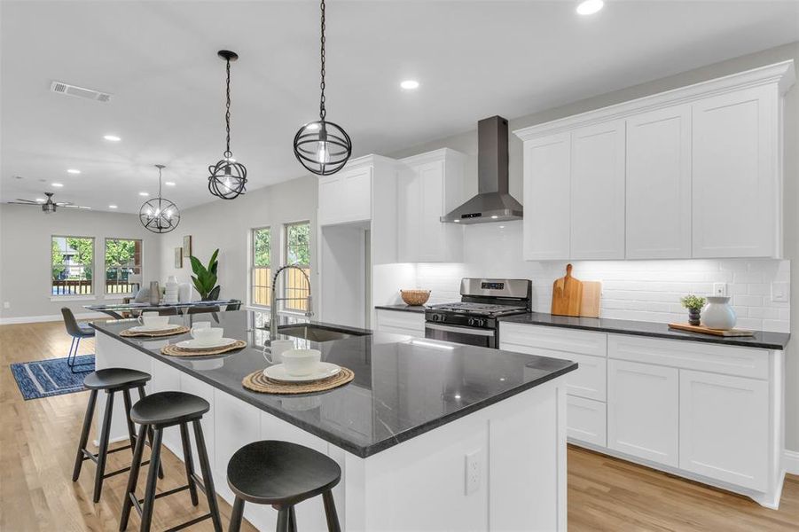Kitchen featuring light wood-type flooring, a breakfast bar, white cabinets, wall chimney exhaust hood, and recessed lighting