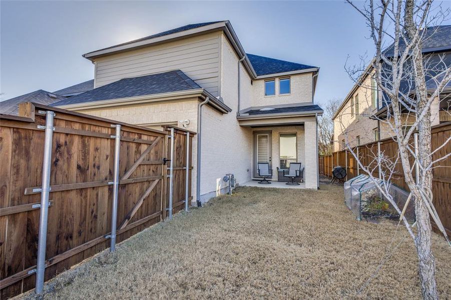 Rear view of house with a patio area, a shingled roof, a gate, brick siding, and a fenced backyard