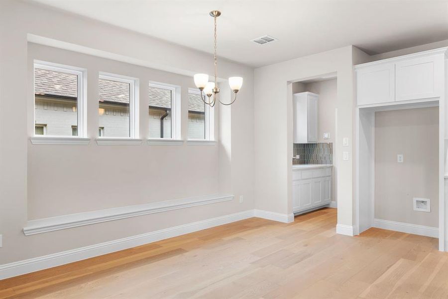 Unfurnished dining area featuring an inviting chandelier and light hardwood / wood-style flooring