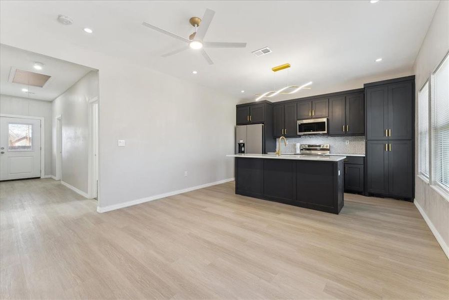 Kitchen featuring appliances with stainless steel finishes, light countertops, visible vents, and light wood-style flooring