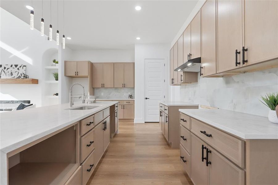 Kitchen featuring light wood finish cabinets, light wood finished floors, pendant lighting, and light stone countertops