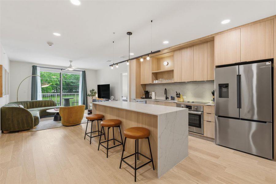 Clean lines and warm wood cabinetry define this modern kitchen and open-concept living area. Clean lines and warm wood cabinetry define this modern kitchen and open-concept living area.