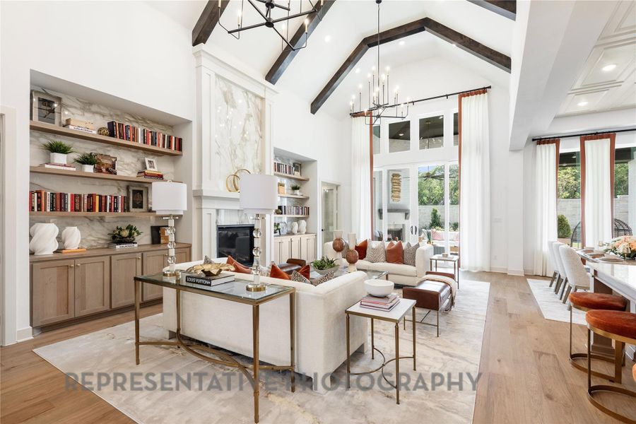 Living room featuring a notable chandelier, high vaulted ceiling, light wood-style floors, and a fireplace Living room featuring a notable chandelier, high vaulted ceiling, light wood-style floors, and a fireplace