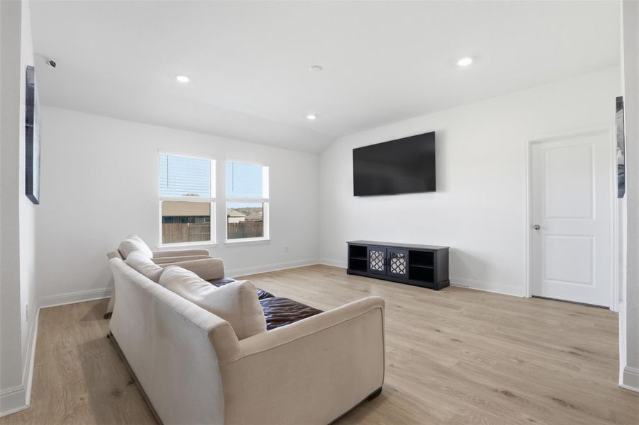 Living space featuring light wood-finish flooring, recessed ceiling lights, and white baseboards