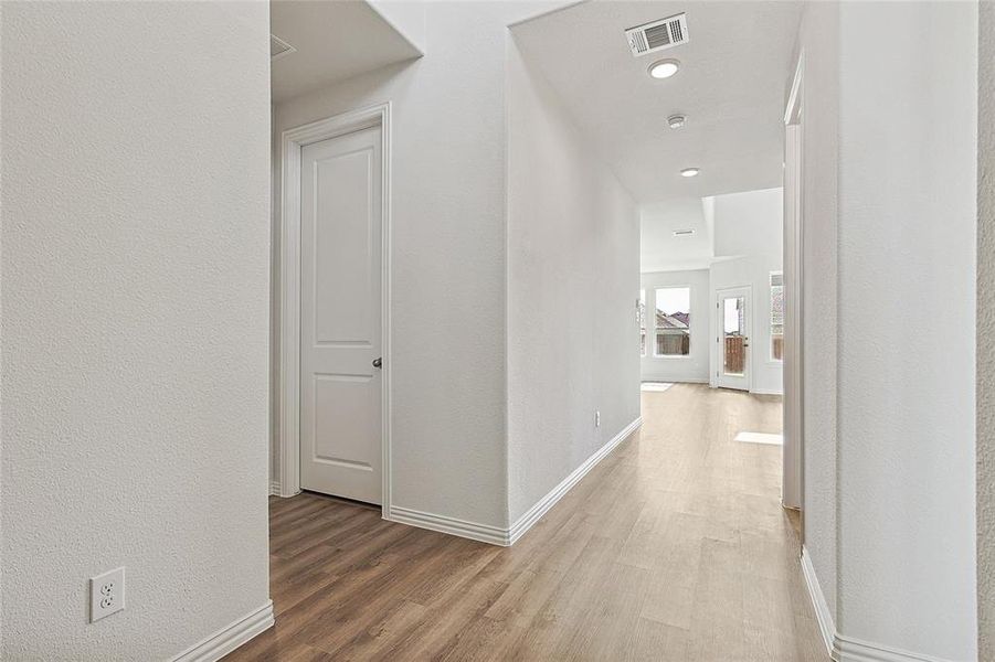 Hallway featuring light wood-type flooring and a textured wall Hallway featuring light wood-type flooring and a textured wall