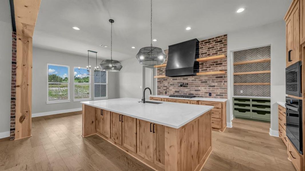 Kitchen featuring a large island with white countertop, wood-finish cabinetry, and industrial-style pendant lighting