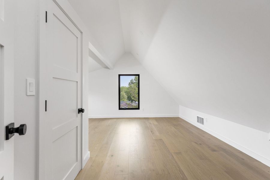 Additional living space with vaulted ceiling and light wood finished floors