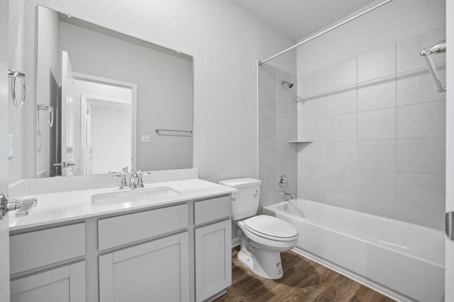 Bathroom featuring shower / bath combination, vanity, and dark wood-type flooring