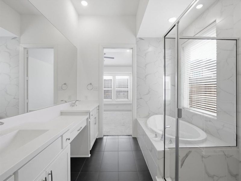 Primary Bathroom with a bath, double vanity, a marble finish shower, recessed lighting, and dark tile patterned flooring