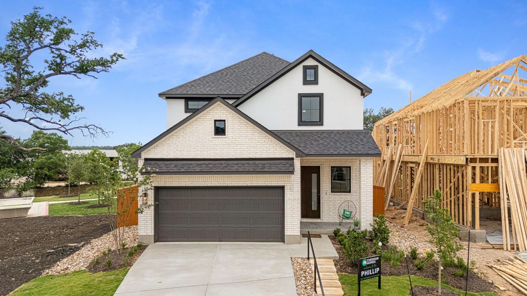 View of front of home with roof with shingles, driveway, stucco siding, brick siding, and an attached garage