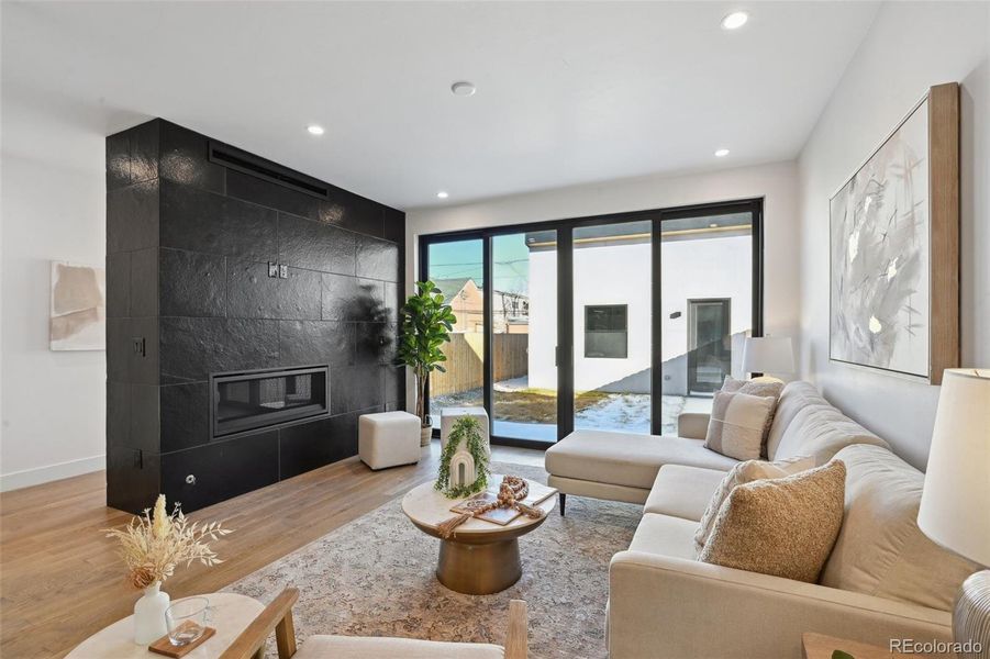 Family room with fireplace, opening onto backyard, mud room space tucked behind fireplace wall next to back entry door