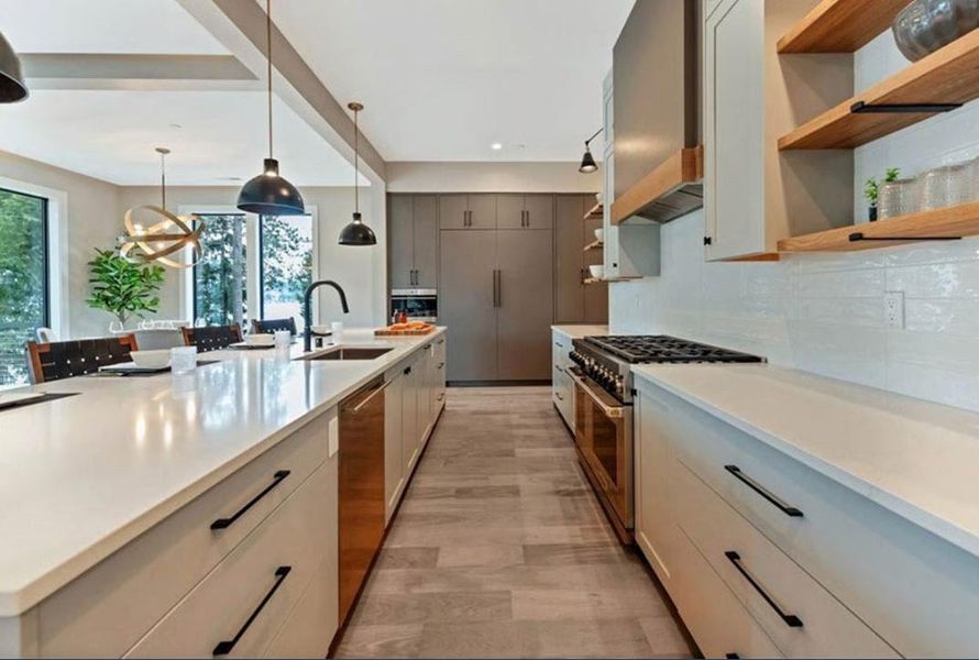Dual tone kitchen featuring stainless steel appliances, two tone cabinets, decorative light fixtures, a large island, and open shelves