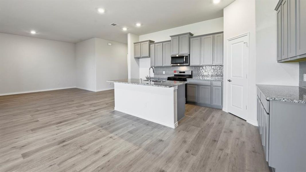 Kitchen featuring gray cabinetry, a kitchen island with sink, light stone countertops, and recessed lighting Kitchen featuring gray cabinetry, a kitchen island with sink, light stone countertops, and recessed lighting