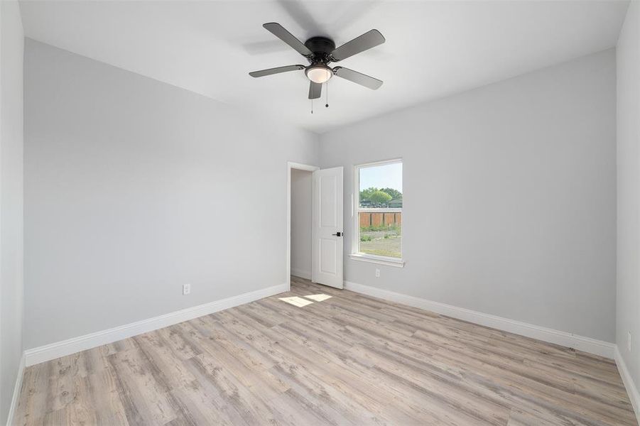 Spare room with light wood-type flooring, baseboards, and ceiling fan