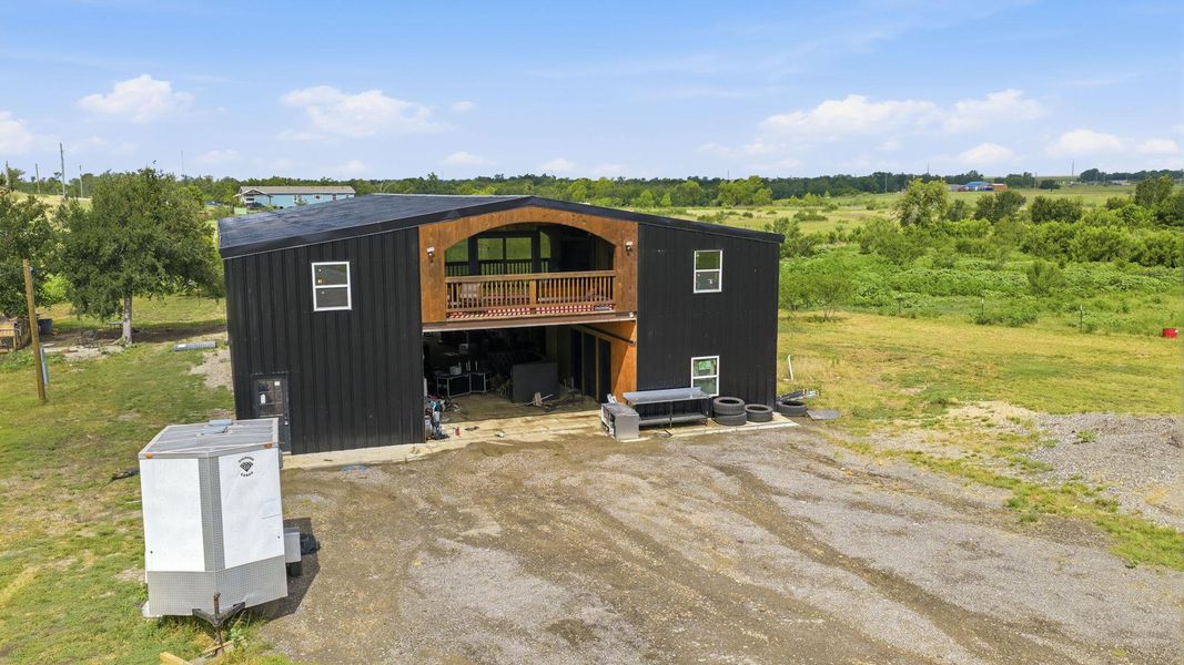 A metal structure with an upper-level balcony overlooks a verdant landscape.
