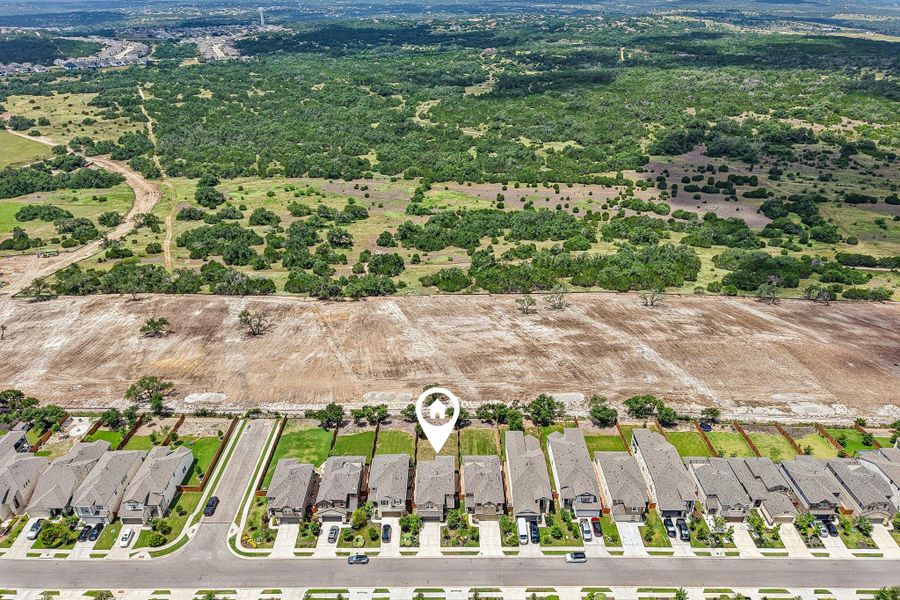 An aerial perspective reveals a prime residential lot nestled between established homes and open, verdant land.