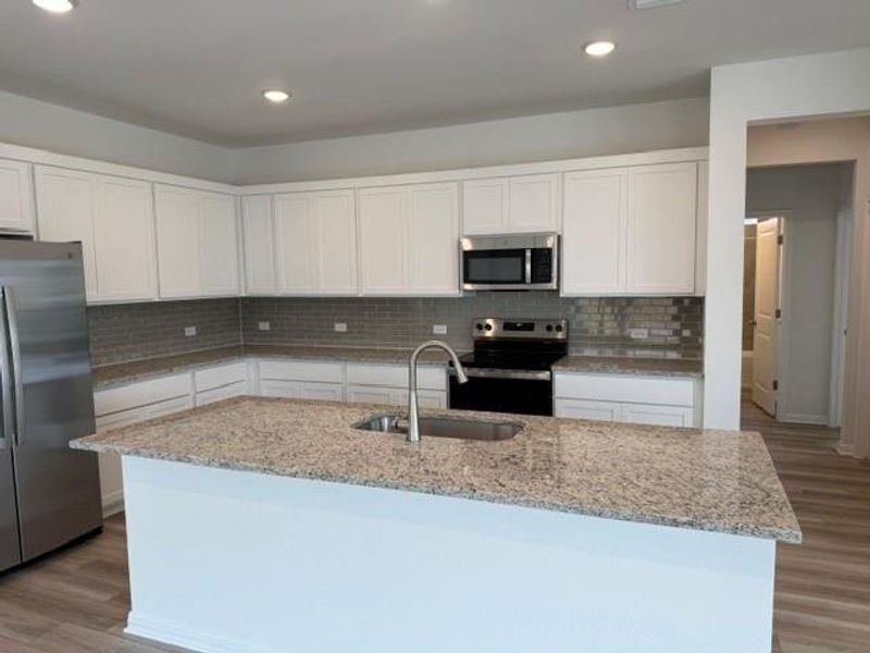 Kitchen featuring a central island with an undermount sink and gooseneck faucet