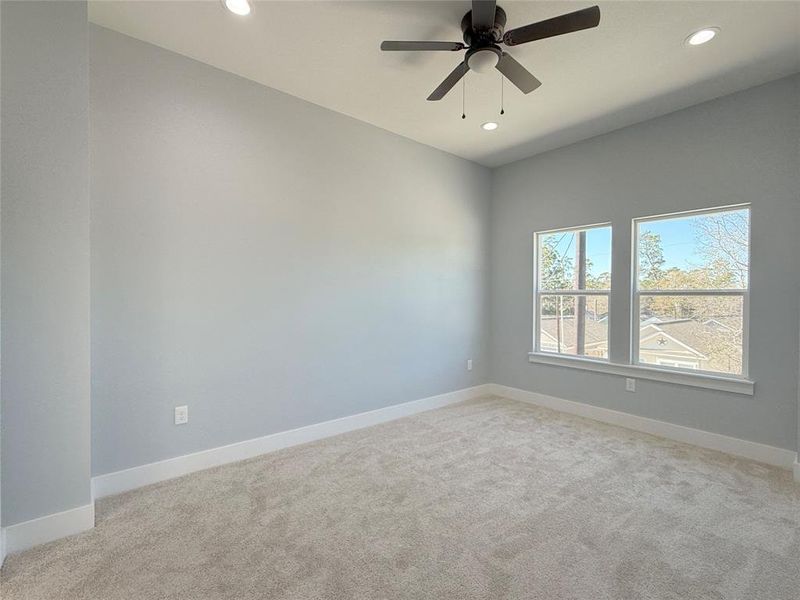 This spacious master suite is beautifully illuminated by abundant natural light through large windows.